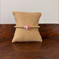 Bracelet with a baseball bead on a burlap pillow against a wooden surface