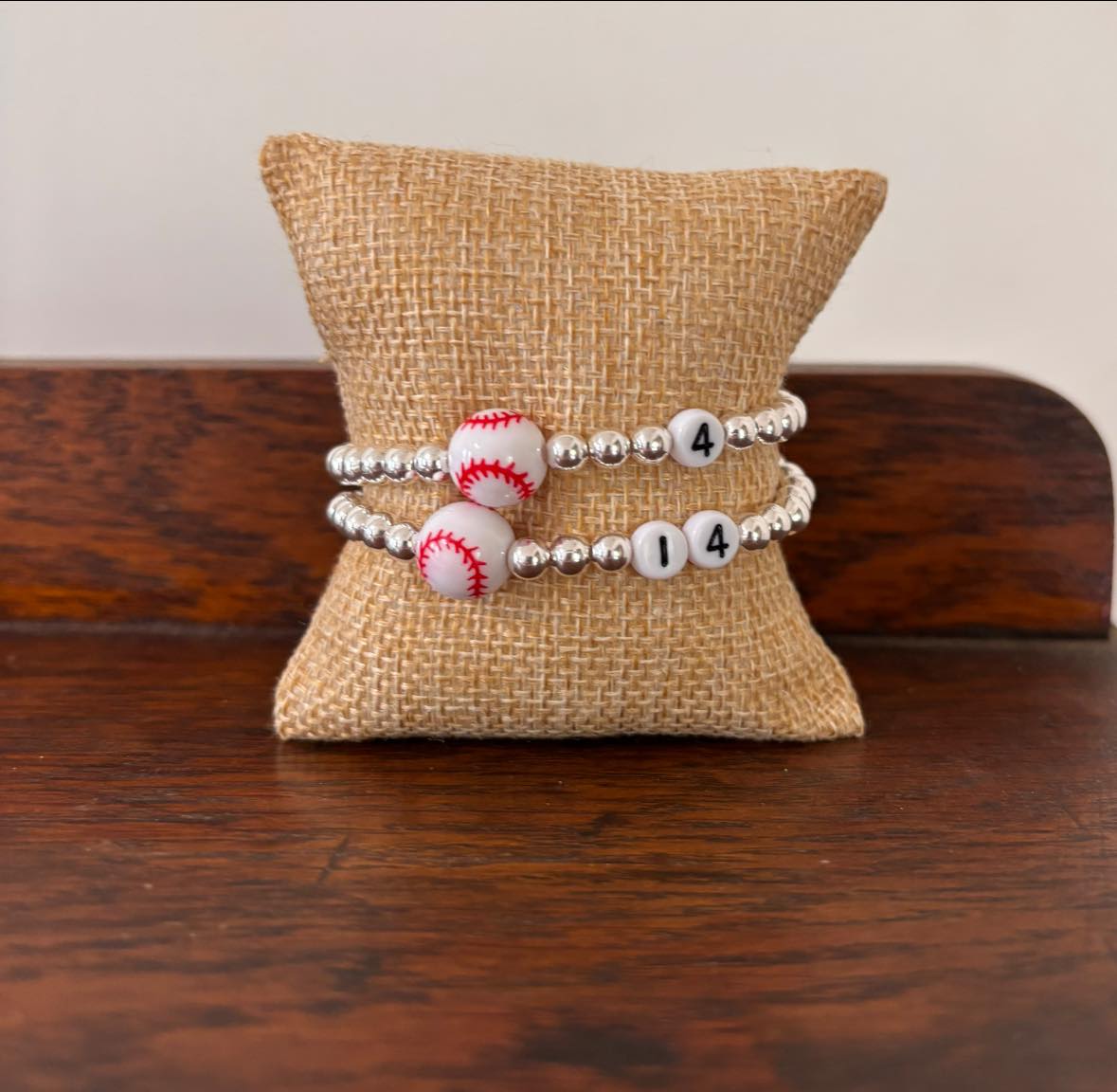 Bracelet with baseball charms and numbers on a textured pillow