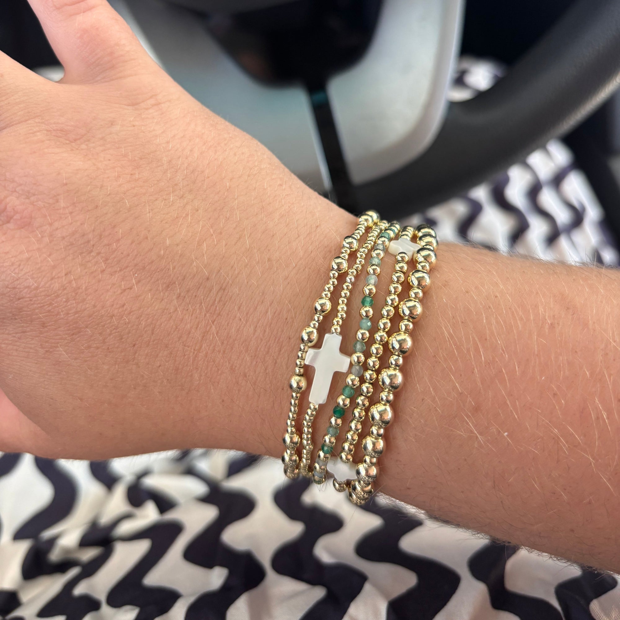 Customized bracelet stack featuring five bracelets of gold beads, pearl accents, and gemstones